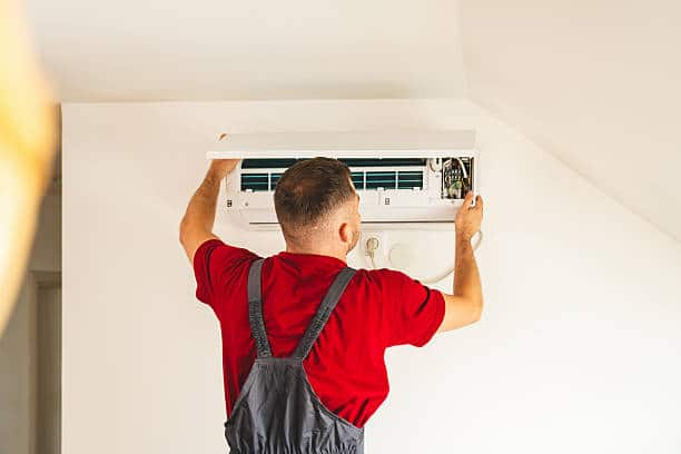 Experienced HVAC technician testing AC electrical components with meter and gauges