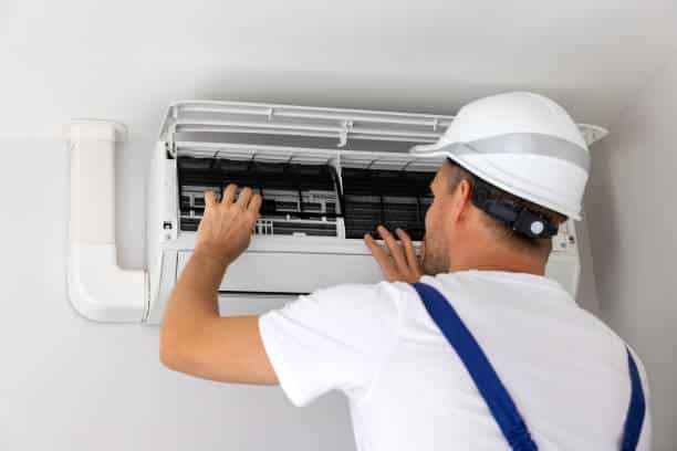 Experienced HVAC technician checking electrical components and airflow during complex AC repair