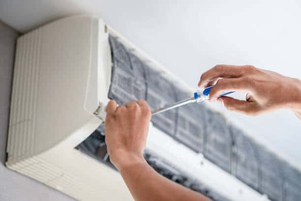 HVAC technician inspecting coastal air conditioning system with diagnostic tools and gauges