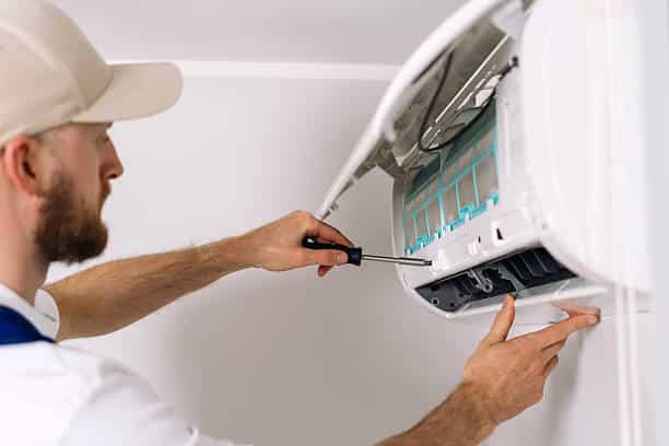 Technician diagnosing residential AC system outside Rumson home during summer cooling failure