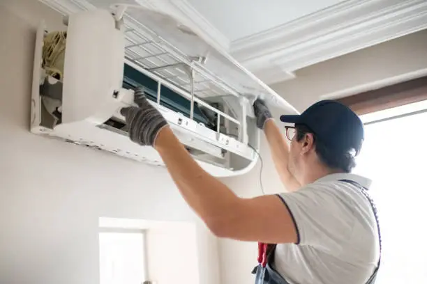 Technician diagnosing failed AC unit during hot afternoon at Howell family home