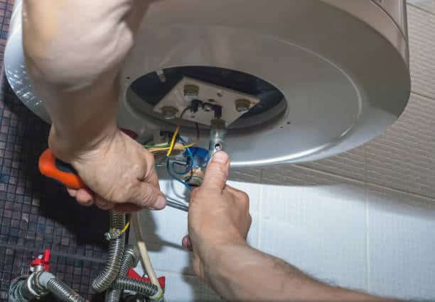 HVAC professional testing furnace components with diagnostic tools and meter