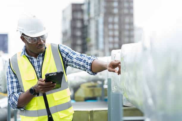 Technician measuring airflow and checking HVAC connections during detailed system commissioning